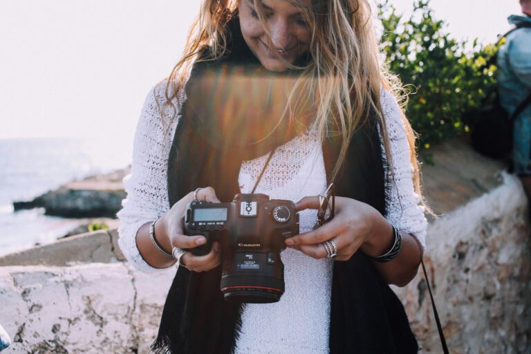 Happy woman checking photos on camera near sea